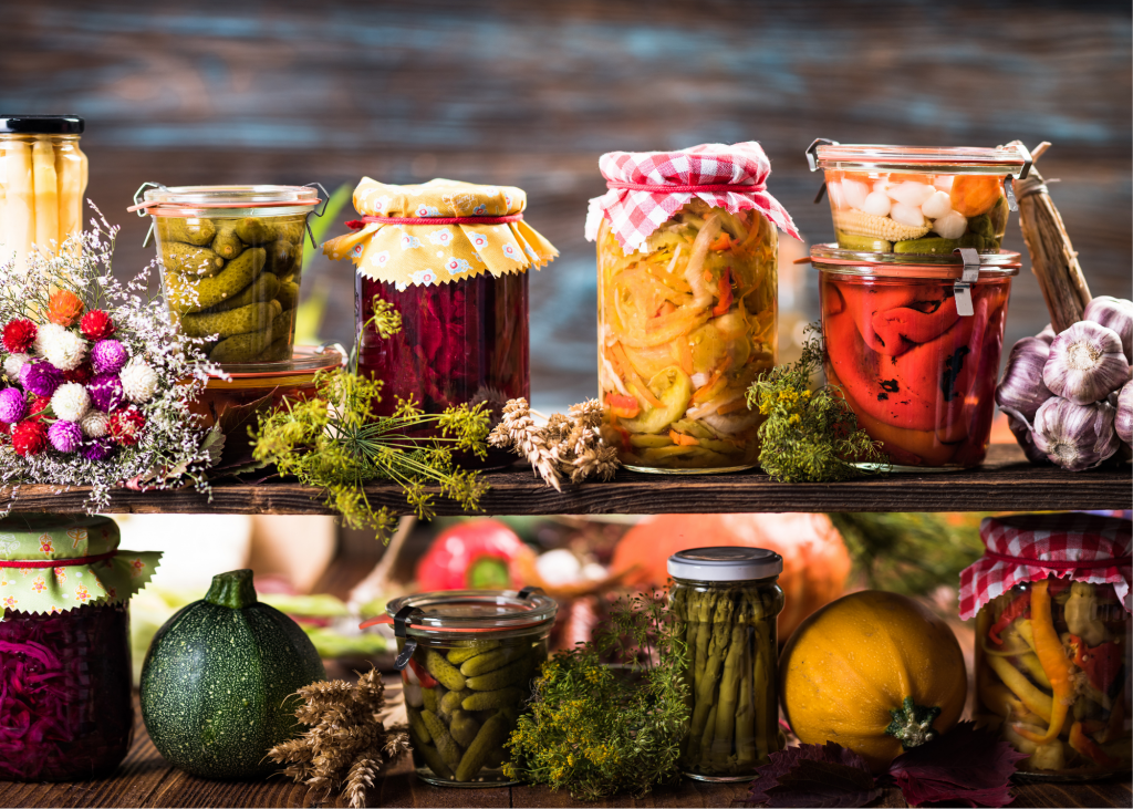 Beneficial fermented foods in jars on shelves with their fresh counterparts sitting beside them.