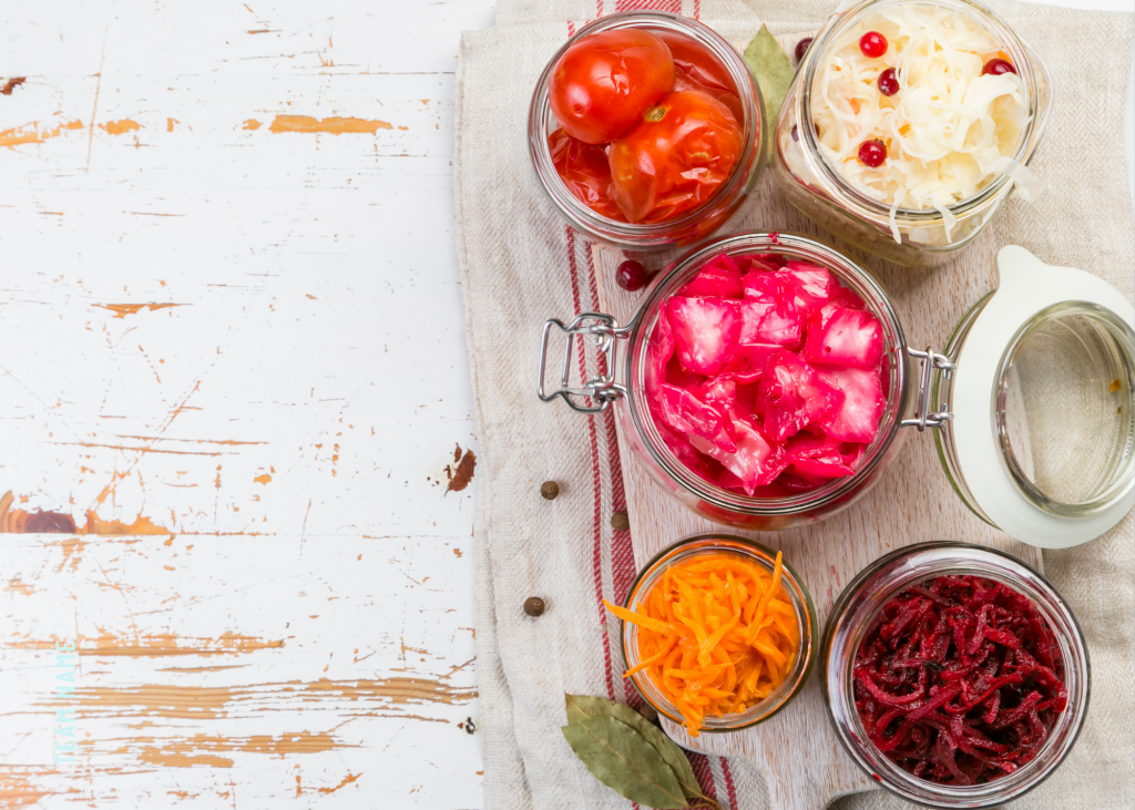 Five swingtop jars full of beneficial fermented foods on white table