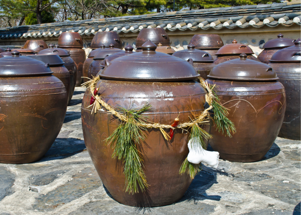 Rows of time tested earthenware fermenting equipment outside on stone with roof of building in background