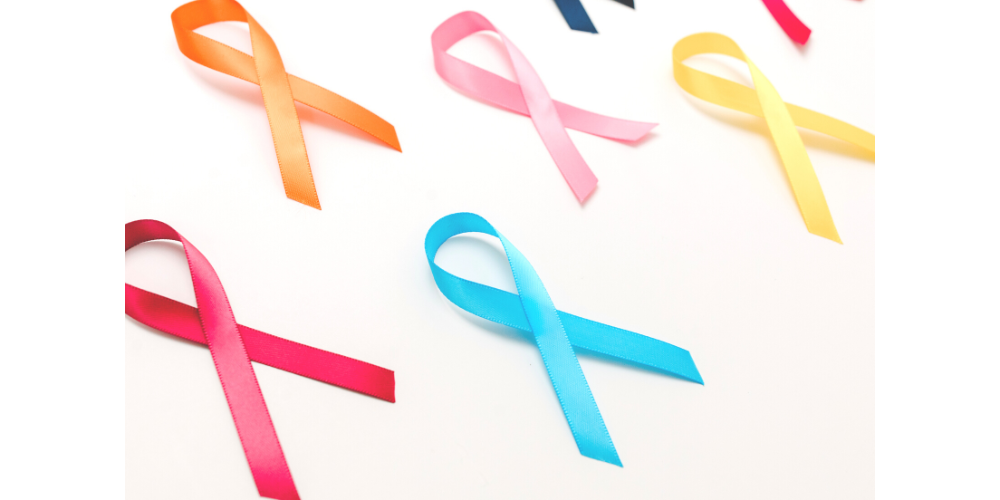 Various colored cancer ribbons laying on white surface.