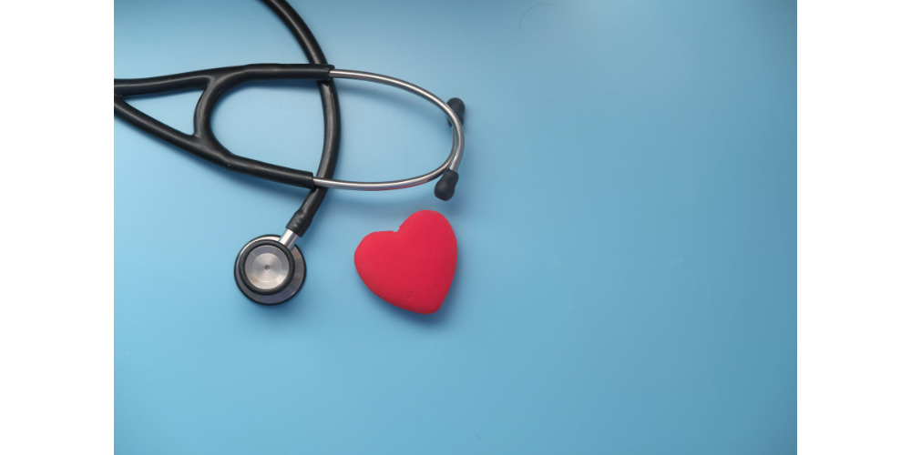 Stethascope and heart shape laying on blue surface.